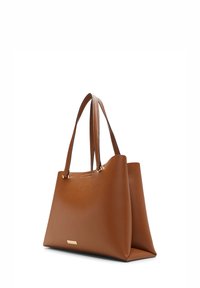 Sac fourre-tout en cuir marron avec une forme structurée, deux poignées, des accents matériels minimalistes et une texture lisse. Plaque de marque en ton doré intégrée.