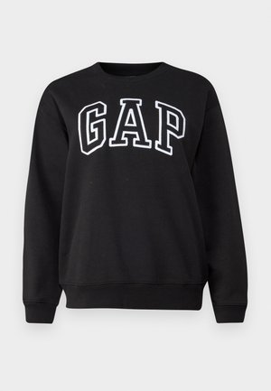 Svart genser laget av bomull med rund hals. Har stor hvit "GAP" tekst på forsiden. Lange ermer og ribbestrikkede mansjetter.