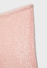 Coin de tissu rose doux avec des petits sequins brillants et denses et une couture festonnée sur un fond clair.