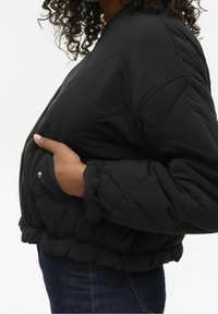 Giacca a vento trapuntata nera con polsini e vita elasticizzati. Presenta una chiusura con zip e tasche laterali, realizzata in un tessuto liscio e isolato.