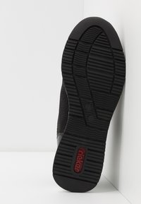 Black shoe sole with textured grip pattern, featuring a red "rieker" logo. The upper part has a woven design, enhancing flexibility and comfort.