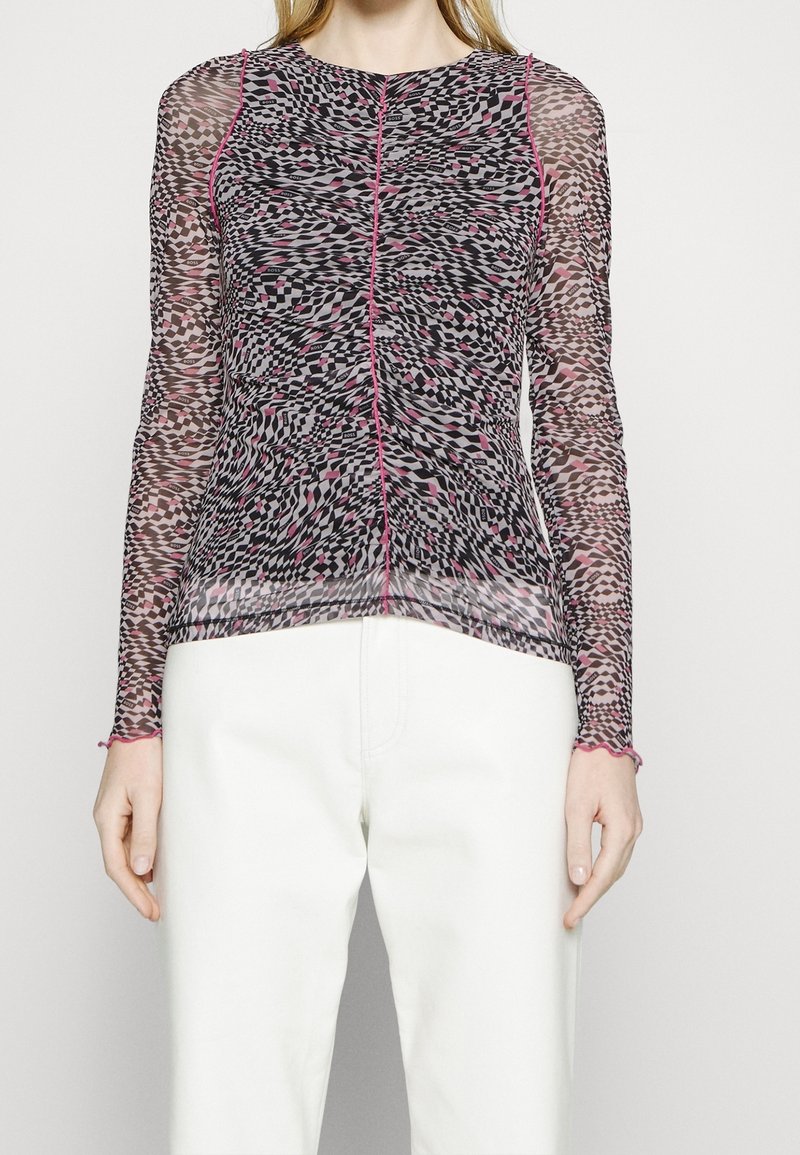 Transparante blouse met lange mouwen, gekenmerkt door een zwart, roze en wit abstract patroon met roze afwerking langs de halslijn en de manchetten.