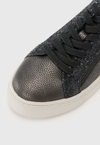 Sneaker nera in tessuto con finitura metallica, dotata di punta arrotondata, lacci neri e suola in gomma bianca a contrasto.
