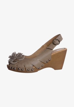 Sandales compensées en cuir marron clair avec un accent floral, des bords festonnés et des clous décoratifs le long de la zone des orteils.
