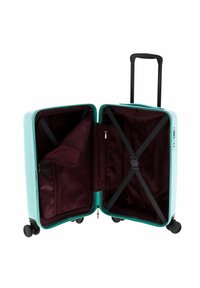 Maleta dura de color turquesa con interior de forro burdeos, correas cruzadas y bolsillo con cremallera; cuenta con cuatro ruedas y un mango retráctil.