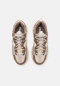 Scarpe sportive marroni e beige con materiali in mesh e suede, dettagli texturizzati, suola bianca spessa e logo sulla linguetta.