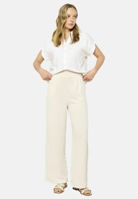 Lightweight, white linen blouse with short sleeves and button closure paired with loose, beige wide-leg pants. Simple, minimalistic design.