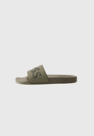 Grüne Gummischlaufsandale mit einem breiten Riemen mit strukturiertem Logo, flacher Sohle und minimalistischer Gestaltung.