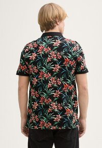 Koszula z krótkim rękawem w czarnym materiale z żywym kwiatowym wzorem w odcieniach różu i zieleni. Standardowy kołnierzyk. Swobodny krój.