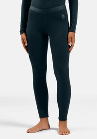 Black leggings made of stretch fabric, featuring a high waistband and a fitted silhouette. Subtle logo detail near the hip. Smooth texture.