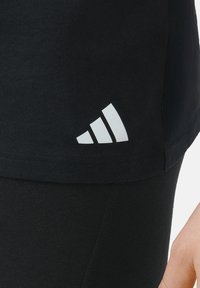Schwarzes Baumwoll-T-Shirt mit einem weißen dreieckigen Logo auf der unteren linken Seite, mit einer weichen Textur und lässiger Passform.