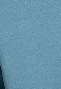 Tela de color azul claro con una textura suave, con un sutil patrón de punto, adecuada para la confección de ropa o tapicería.
