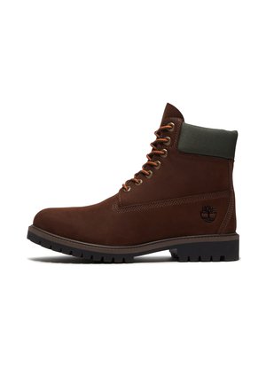 Brauner Leder-Schnürstiefel mit gepolstertem dunkelgrünem Kragen, dicker schwarzer Sohle und geprägt Logo an der Fersenseite.