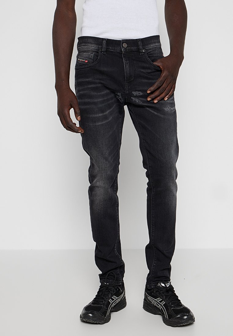 Schwarze Denim-Jeans mit slim Fit, die leicht verwaschen und dezent gefädelt sind. Abgeschlossen mit einem Knopfverschluss und seitlichen Taschen.