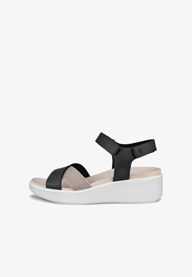 Sort og beige sandal med justerbar ankelrem, polstret indersål og hvid kilehæl, velegnet til afslappet brug.