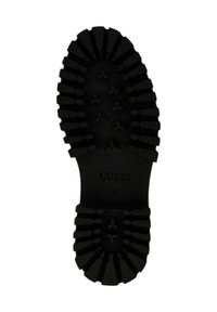 Sole di scarpa nera con scanalature profonde, caratterizzata da motivi triangolari e testo "GUESS 37" stampato al centro.