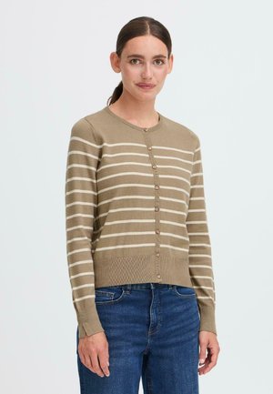 Beige cardigan med kremfargede striper, med rund hals og knappelukking, fullført med ribbestrikkede mansjetter og nederkant. Brukt sammen med blå jeans.