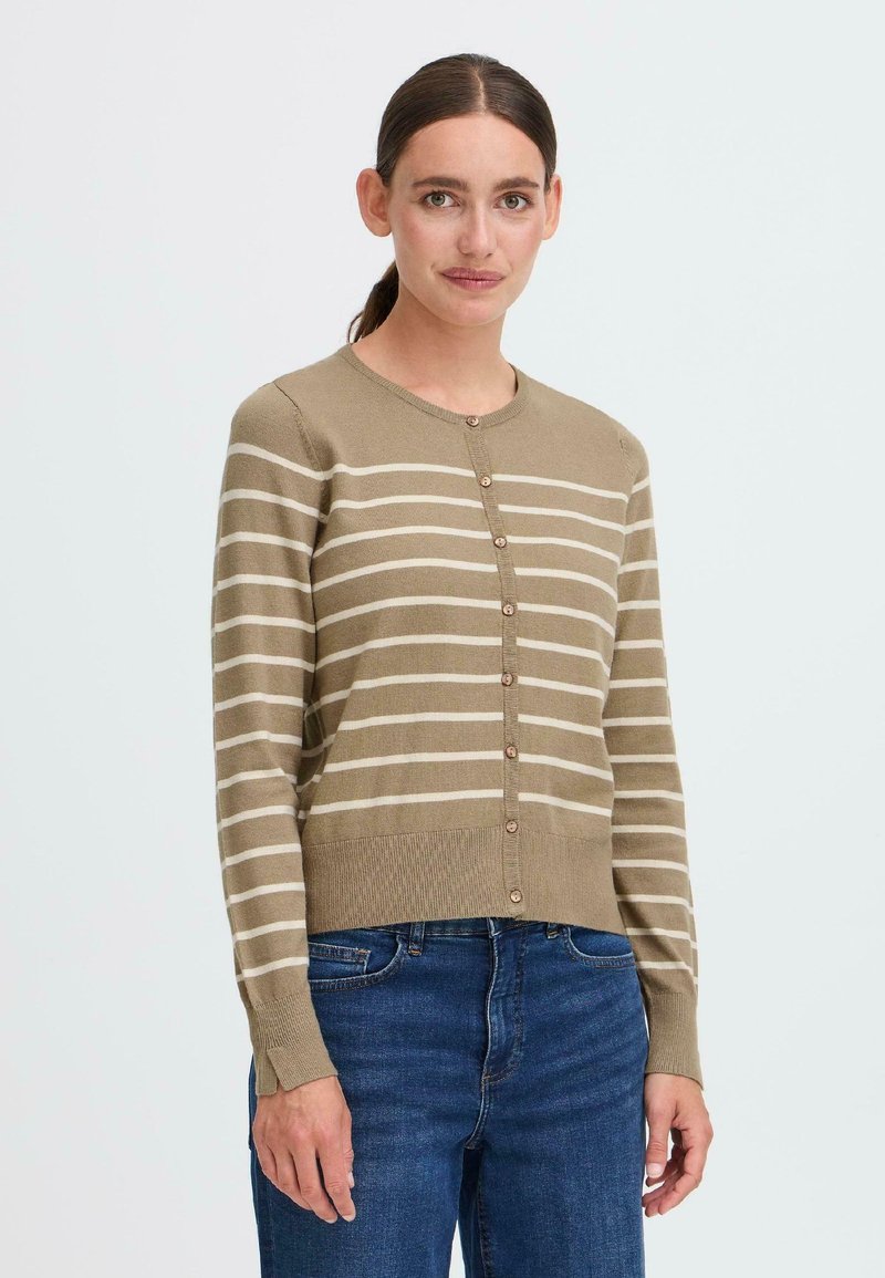 Beige cardigan med kremfargede striper, med rund hals og knappelukking, fullført med ribbestrikkede mansjetter og nederkant. Brukt sammen med blå jeans.