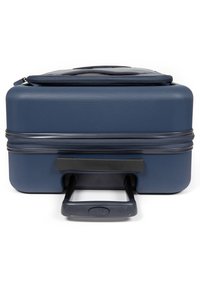 Valigia rigida, blu navy, superficie texturizzata. Manico black estensibile che fuoriesce dalla base. Compartmento superiore con zip visibile.