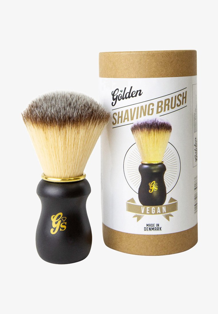 Vegan rakborste med svart ergonomisk handtag och mjuka borst, presenterad bredvid cylindrisk pappförpackning märkt "Golden."