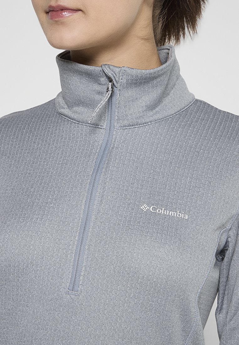 Sudadera de forro polar gris con un patrón texturizado. Presenta un collar alto y el logo de Columbia en el lado izquierdo del pecho. Tela suave y ligera.