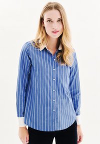 Blau gestreiftes Hemd mit Knöpfen, das lange Ärmel, einen weißen Kragen und Manschetten hat. Der Stoff hat eine glatte Textur mit vertikalen Streifen und einem abgerundeten Saum.
