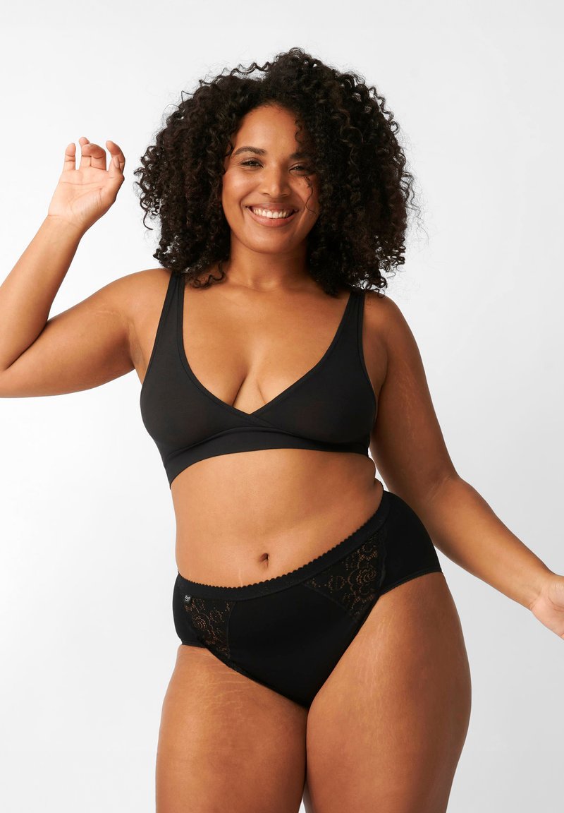 Bralette nera con scollatura a V e spalline larghe, abbinata a slip neri con dettagli in pizzo sui lati. Texture liscia.