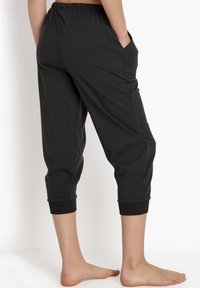 Zwarte katoenen enkelbroeken met een elastische tailleband en zijzakken. Voorzien van ribbelboorden aan de onderkant. Glad materiaal, relaxed fit.