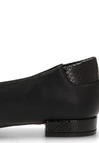 Zapato negro de cuero tipo mocasín con tacón bajo y detalles texturizados en estampado de serpiente en el tacón y el borde de la suela.