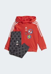 Felpa rossa con cappuccio e strisce bianche, arricchita da toppe Marvel, abbinata a pantaloni della tuta grigi con icone di supereroi nere e etichetta del logo.