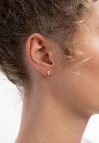 Boucles d'oreilles à clou en pierre précieuse ronde et transparente, montées dans un petit support en métal brillant. Leur design simple complète divers styles.