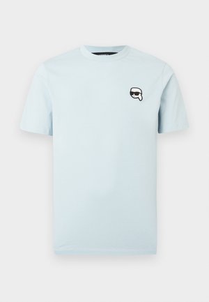 Tricou din bumbac bleu deschis, cu mâneci scurte, decolteu rotund și un grafic mic al unui personaj purtând ochelari de soare pe partea stângă a pieptului.