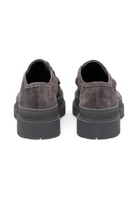 Une paire de chaussures à plateformes en suède gris foncé vue de l'arrière, avec des semelles en caoutchouc épais et rainuré, sur fond blanc.