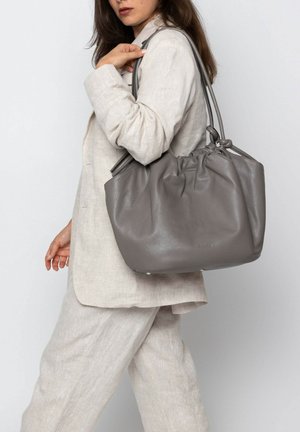 Grey leather tote bag with a cinched top, dual handles, and a smooth texture, displaying a rounded shape and small hardware details.