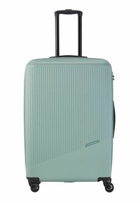 Valise rigide de couleur vert menthe clair, avec une texture nervurée verticale, une poignée télescopique noire et quatre roues noires pour la mobilité.