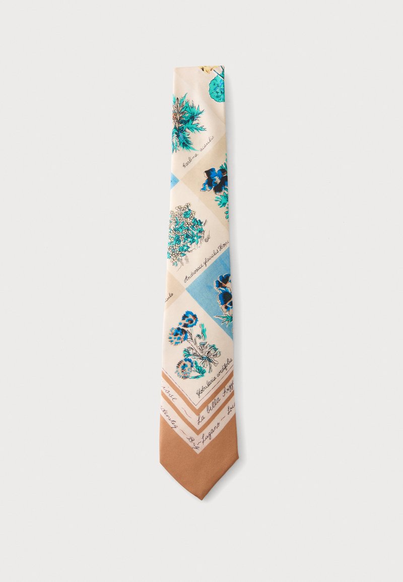 Cravate en soie avec motifs floraux bleus et verts sur fond beige, terminée par une pointe marron unie, posée à plat sur une surface blanche.
