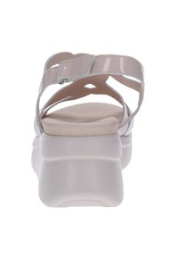 Sandalias en un material rosa claro brillante con una correa ajustable en el tobillo, diseño cruzado y una suela gruesa blanca.