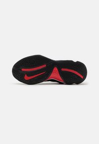 Semelle de basket Nike noire et rouge avec motifs antidérapants texturés et logo Nike swoosh visible sur fond blanc.