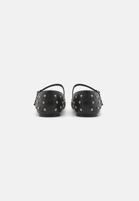 Black leather shoes with a low heel, featuring silver studs evenly spaced across the surface, and a slingback design.