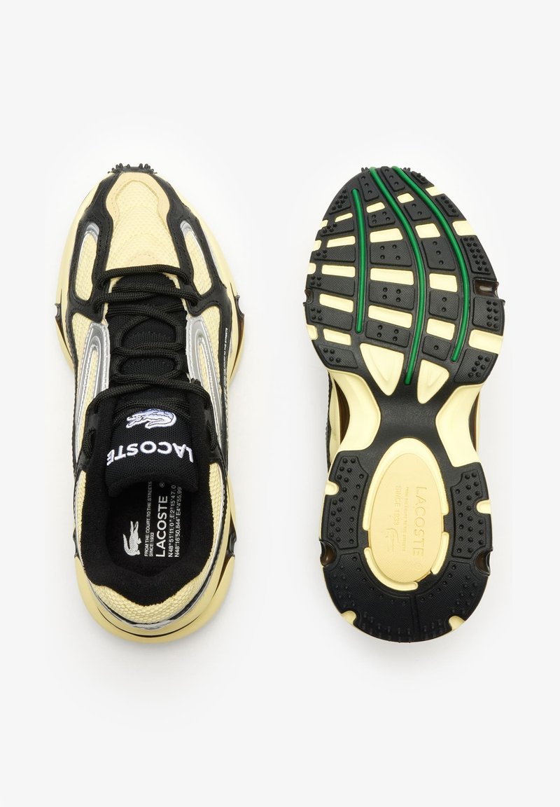 Chaussures de sport noires et jaunes en matériau mesh et synthétique, avec une semelle texturée, un col rembourré et des accents argentés contrastés.