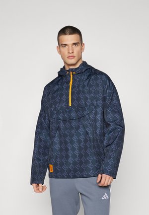 Giacca a vento blu navy con motivo geometrico, dotata di zip frontale con dettagli arancioni, cappuccio e maniche lunghe.