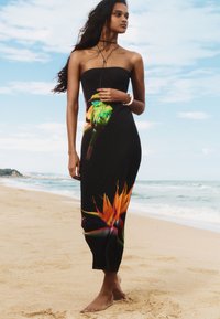 Black strapless dress featuring a vibrant parrot and bird of paradise print, made of lightweight fabric, with a fitted design and ankle length.