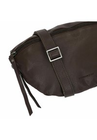 Borsa a tracolla in pelle marrone con una fibbia quadrata in argento, chiusura con zip e lunghe cinghie. Presenta una finitura testurizzata e un branding sottile.