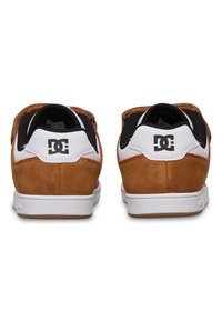 Braune Wildleder-Sneaker mit weißen Akzenten, abgerundeter Spitze, strukturiertem Fersenbereich und schwarzem Mesh-Futter. DC-Logo an der Ferse in kontrastreicher Farbe.