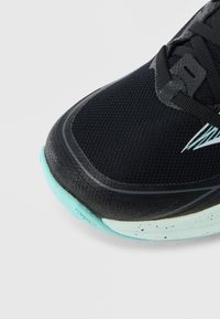 Μαύρο αθλητικό παπούτσι με ανώτερο μέρος από διαπνέον διχτυωτό υλικό, τυρκουάζ εξωτερική σόλα και γκρι λεπτομέρειες. Διαθέτει στρογγυλερή μύτη και υφή επιφάνειας.