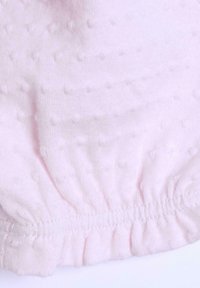 Tessuto a maglia rosa con un motivo testurizzato di piccole macchie rialzate, caratterizzato da un orlo elastico arricciato e un aspetto morbido e leggero.