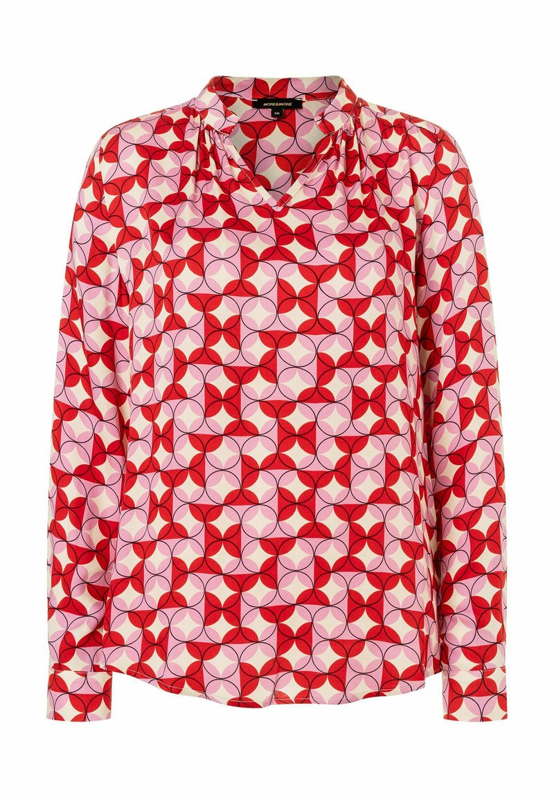 Lange mouwen blouse in rode, roze en crèmekleurige stof. Heeft een geometrisch patroon met cirkels en bloemblaadjes. V-halslijn en geplooide schouderdetails.