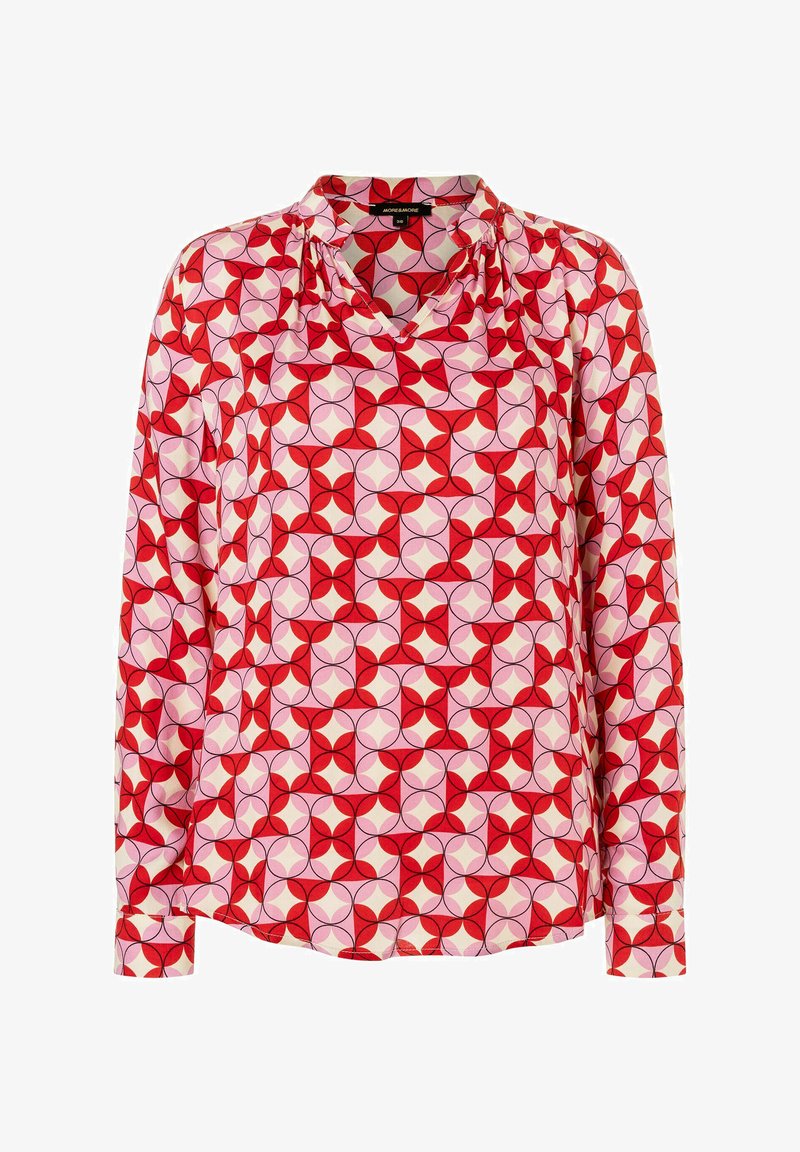 Lange mouwen blouse in rode, roze en crèmekleurige stof. Heeft een geometrisch patroon met cirkels en bloemblaadjes. V-halslijn en geplooide schouderdetails.