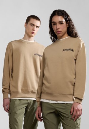 Felpe in cotone beige con polsini e orlo a coste, con un logo nero sul petto, abbinate a pantaloni cargo verdi.