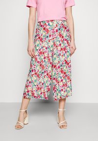 Pantalon culotte floral avec un motif coloré comprenant du rouge, du rose, du vert et du jaune sur un fond clair, fabriqué en tissu léger.
